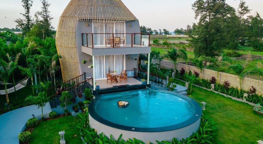Completed bamboo-clad house with balconies beside a circular pool